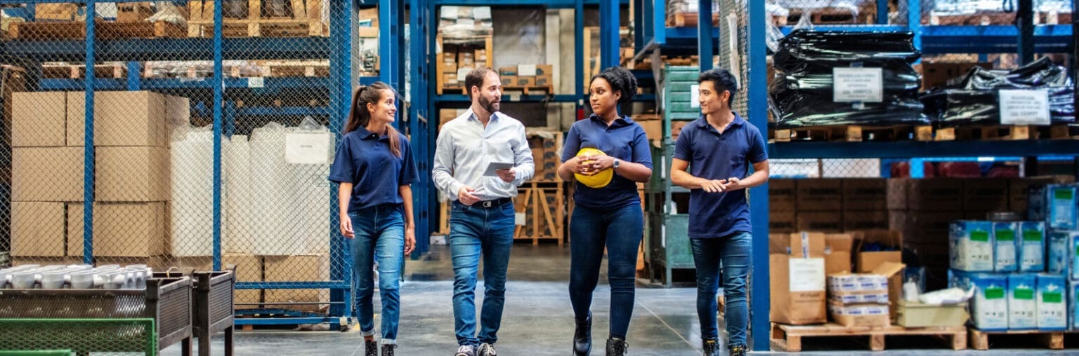 Zwei Frauen und zwei Männer in einer Lagerhalle vor Regalen